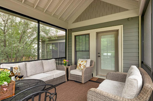 Screened in porch with green walls and white couches.