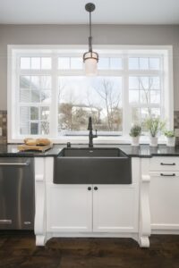 Black sink surrounded by white cabinetry.