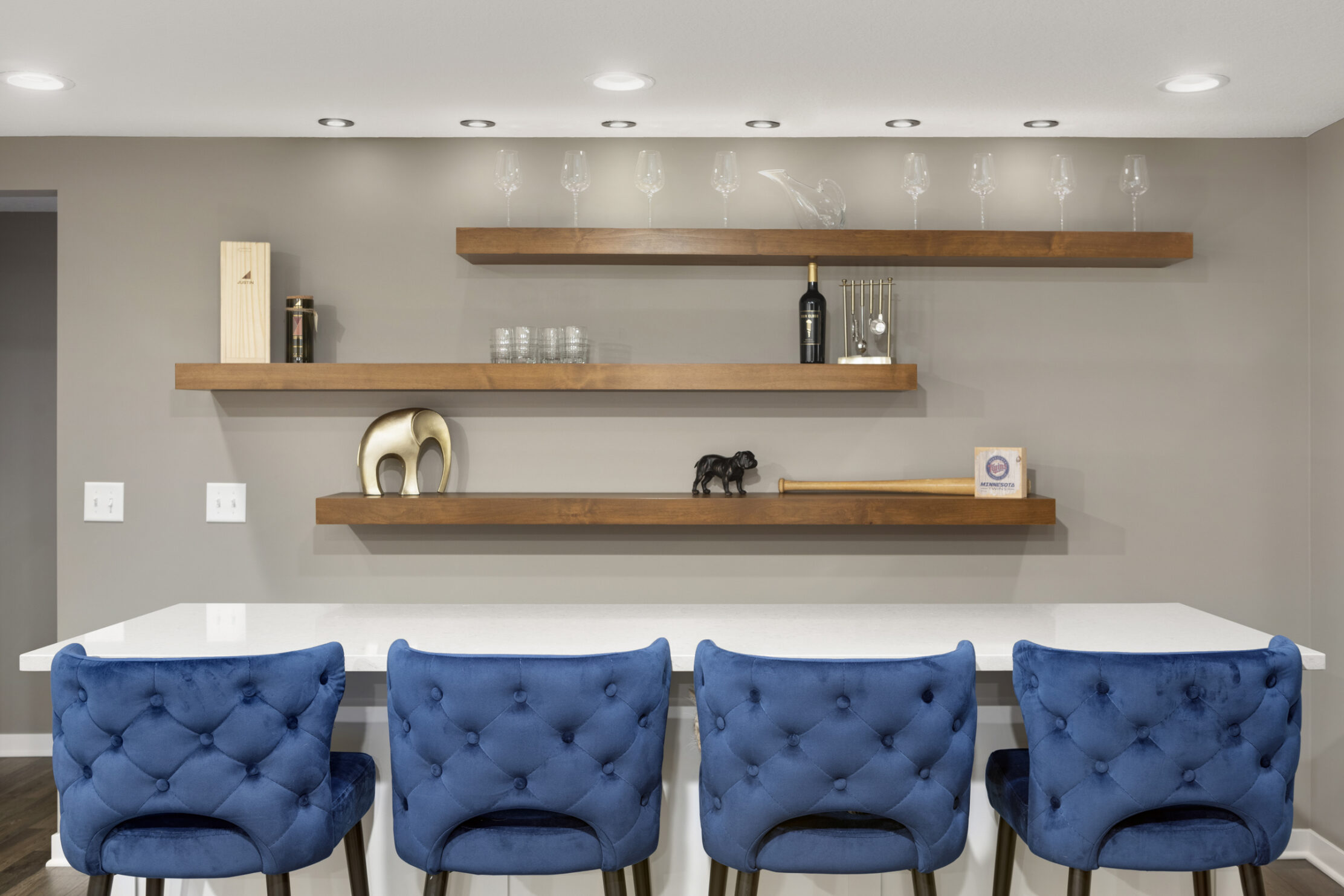 Basement remodel in Minneapolis, Minnesota with blue chairs and floating shelves against a gray wall.