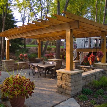 A large wooden pergola built over a stone patio