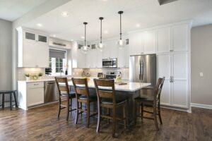 Remodeled kitchen with dark hardwood flooring, white cabinets, and pendant lights. 