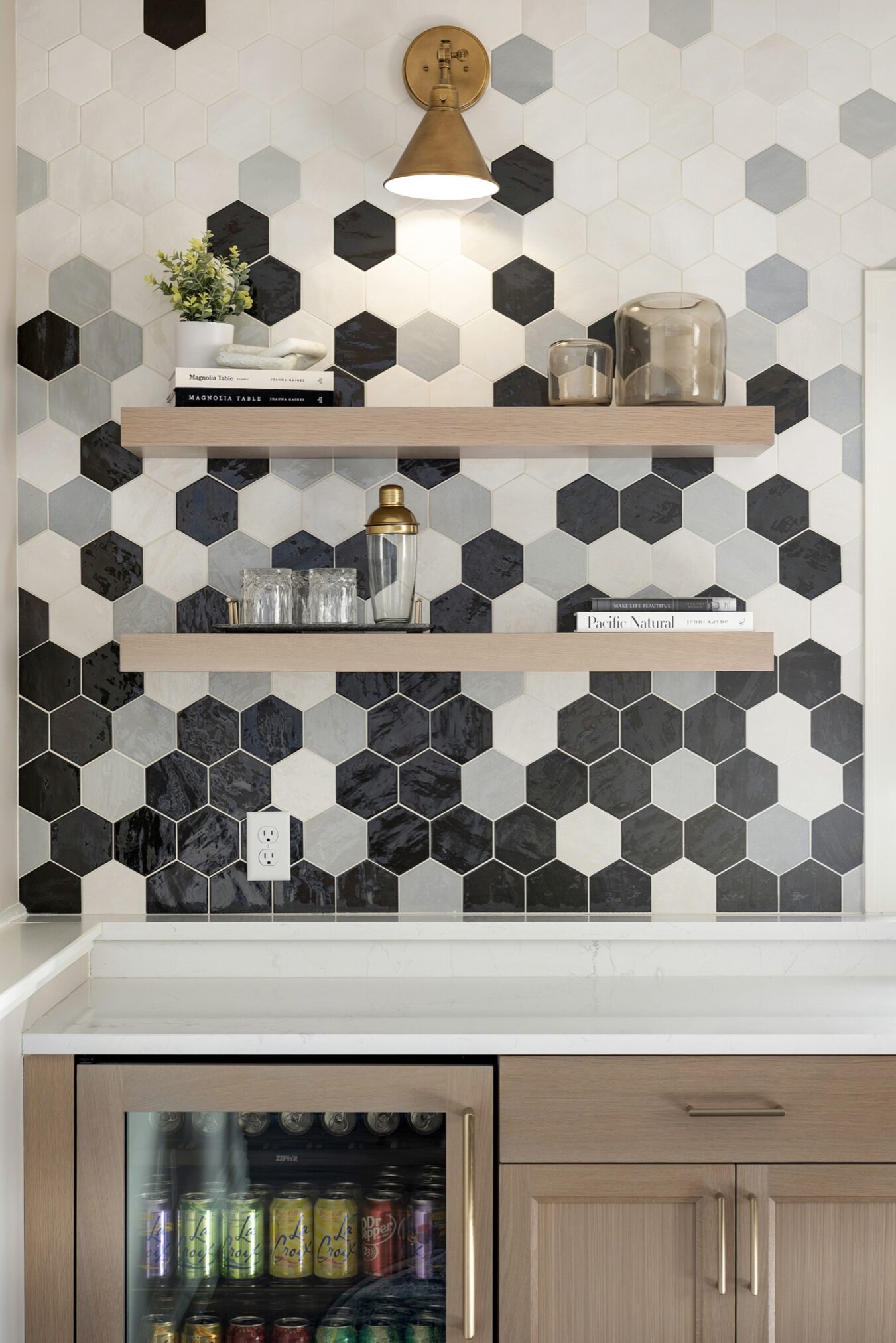 Wet bar with custom tile backsplash and floating shelves hit up by light fuxtures.