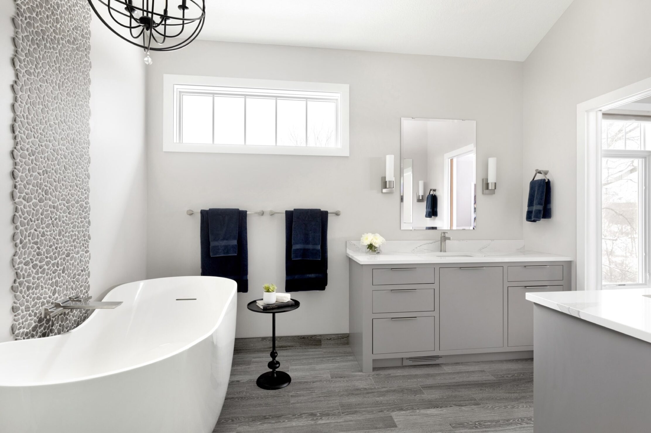 White and black bathroom with tub, towels, and tiled wall.