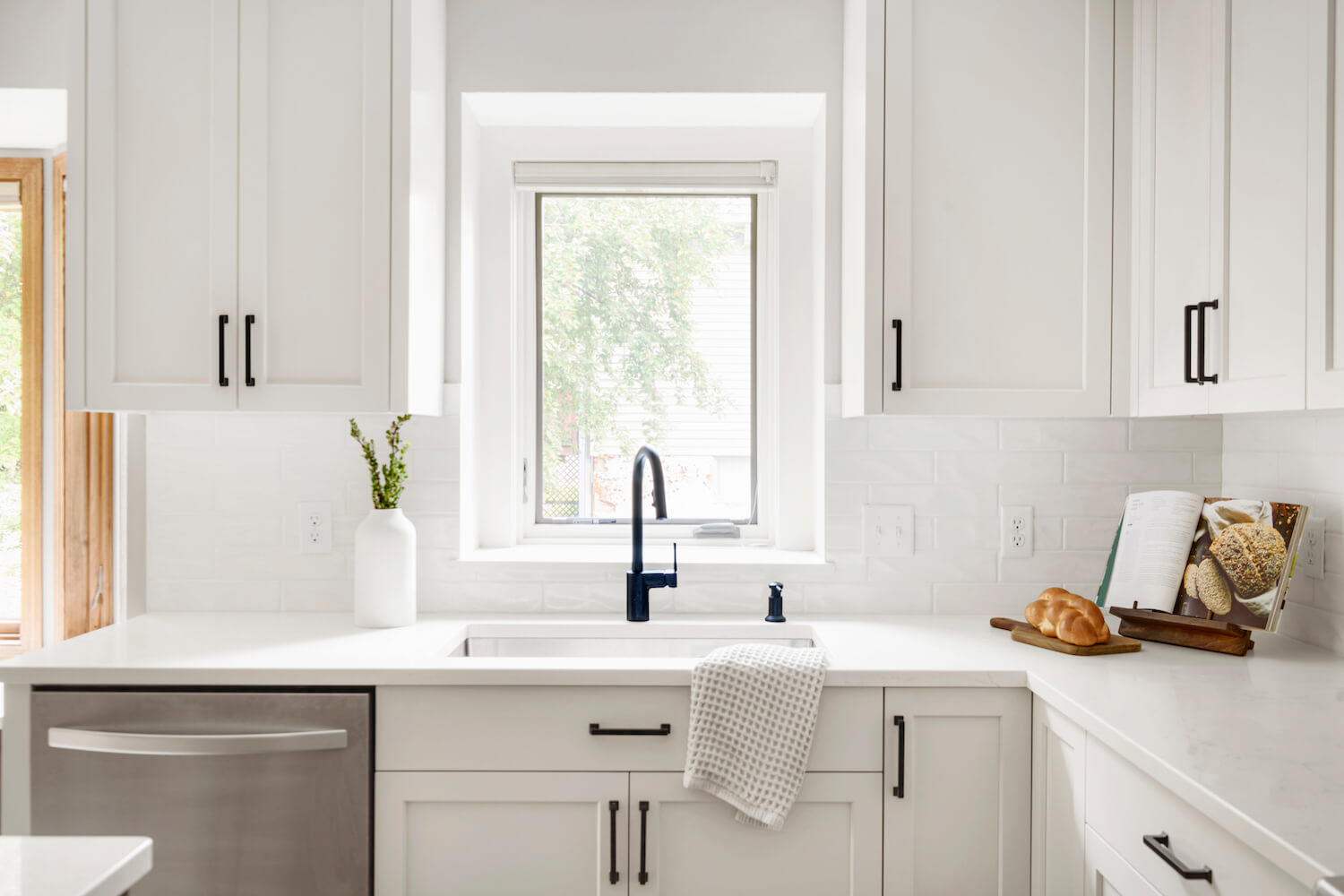 A very tidy looking white kitchen sink on a white countertop