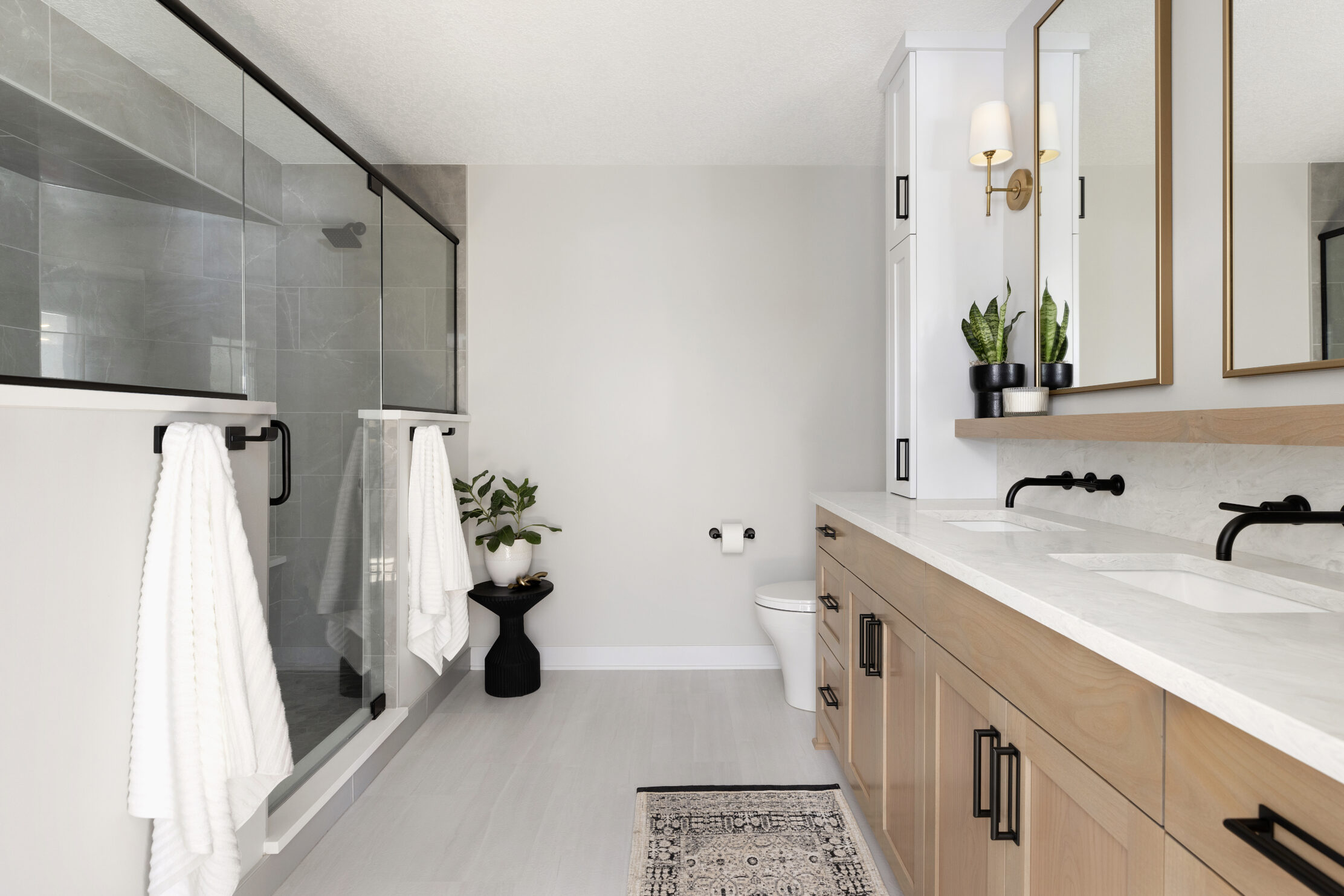 Bathroom remodel with white countertops and wooden cabinetry. 