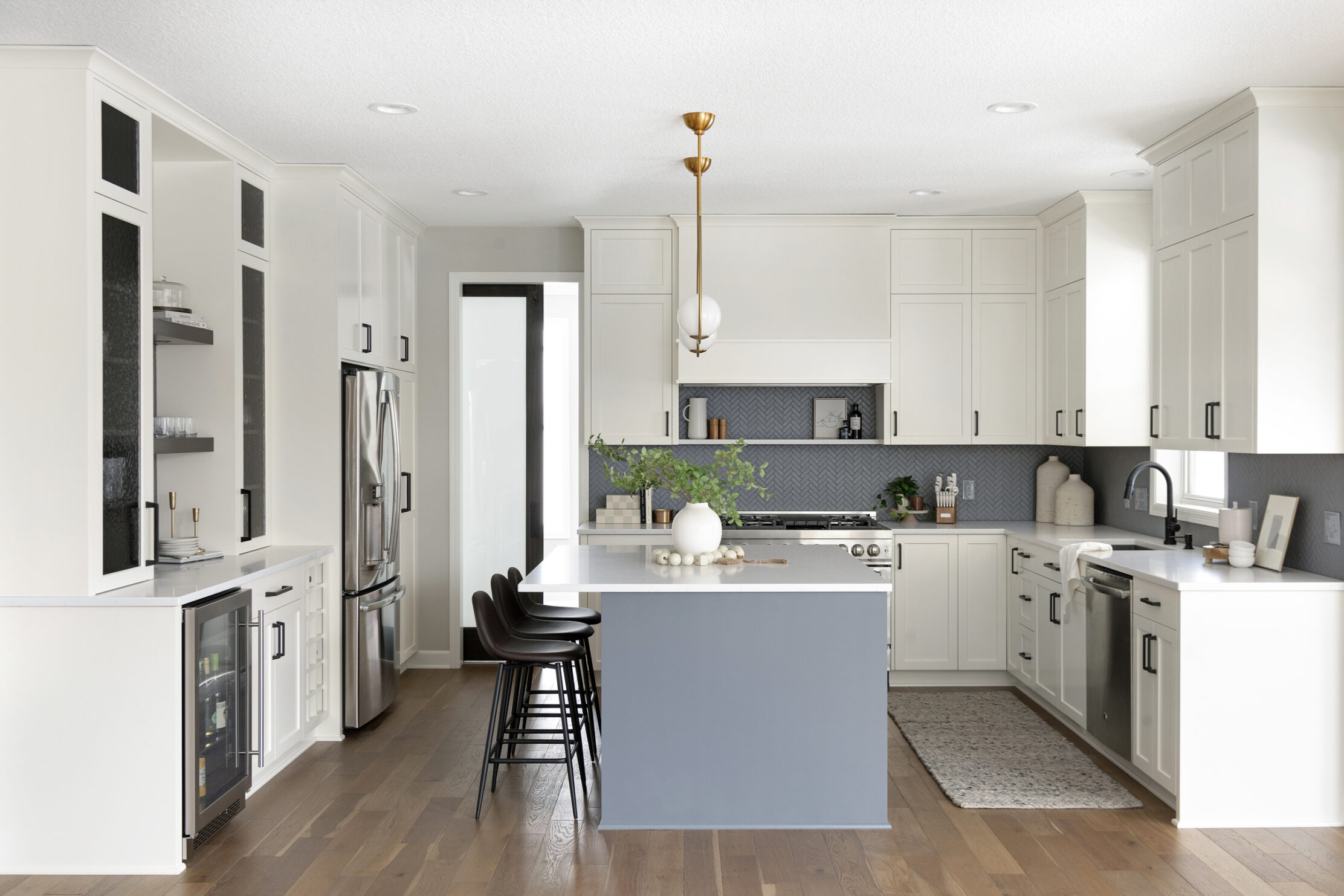 Kitchen remodel with white walls and cabinetry, light blue island and golden light fixtures. Part of the 2023 Parade of Homes MN Remodelers Showcase.