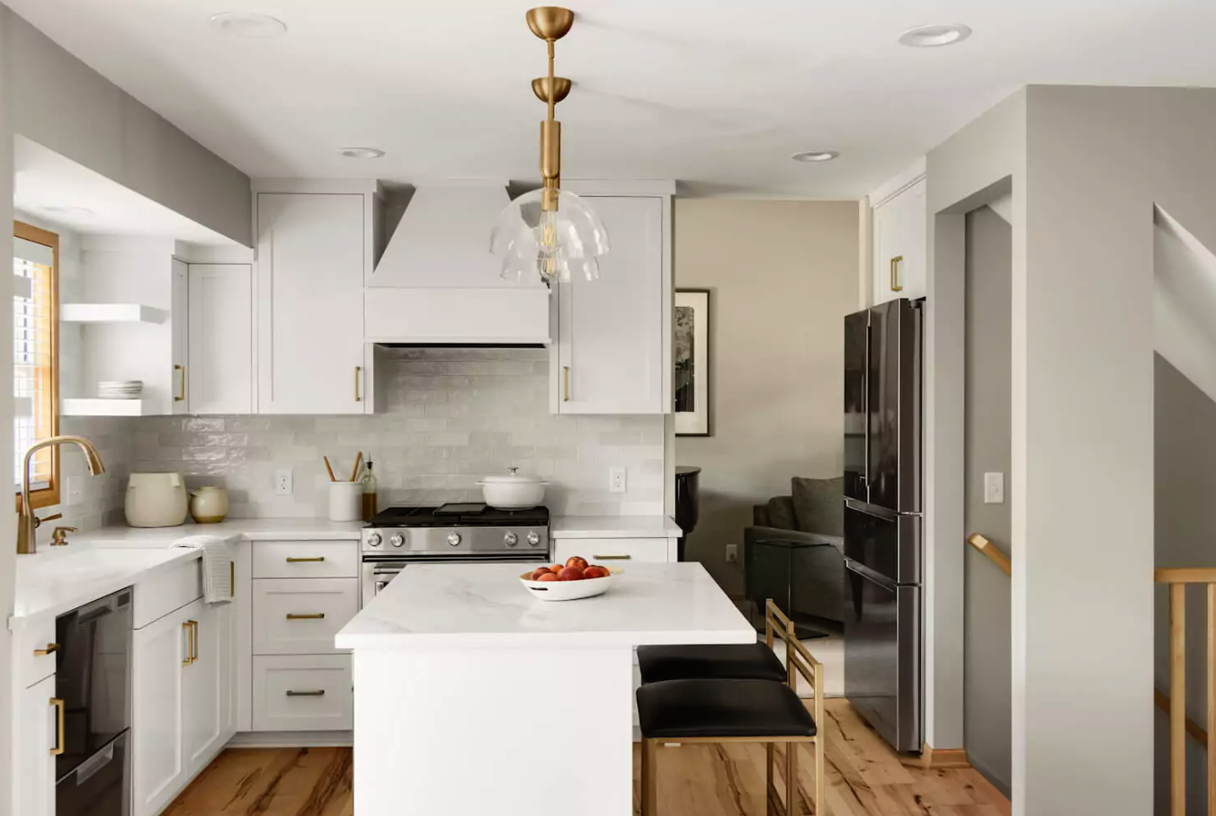 bright white kitchen countertops with stainless appliances and gold fixtures, light wood floors