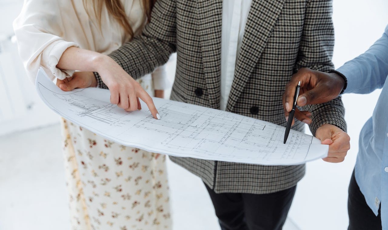Three people looking at a drawing for a floor plan