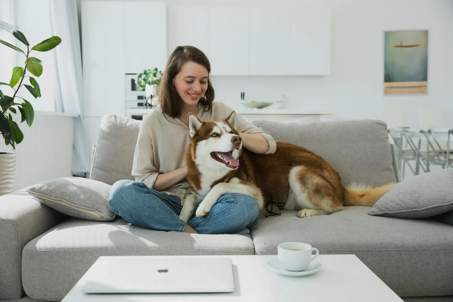 Woman sitting with a husky dog on a couch