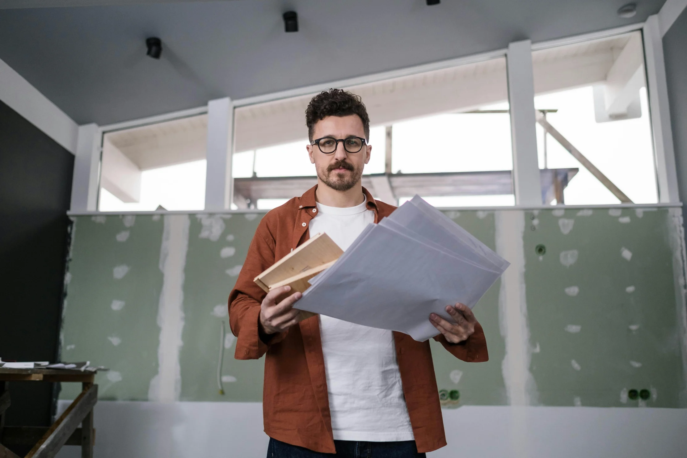 man holding blueprints in a home undergoing renovation