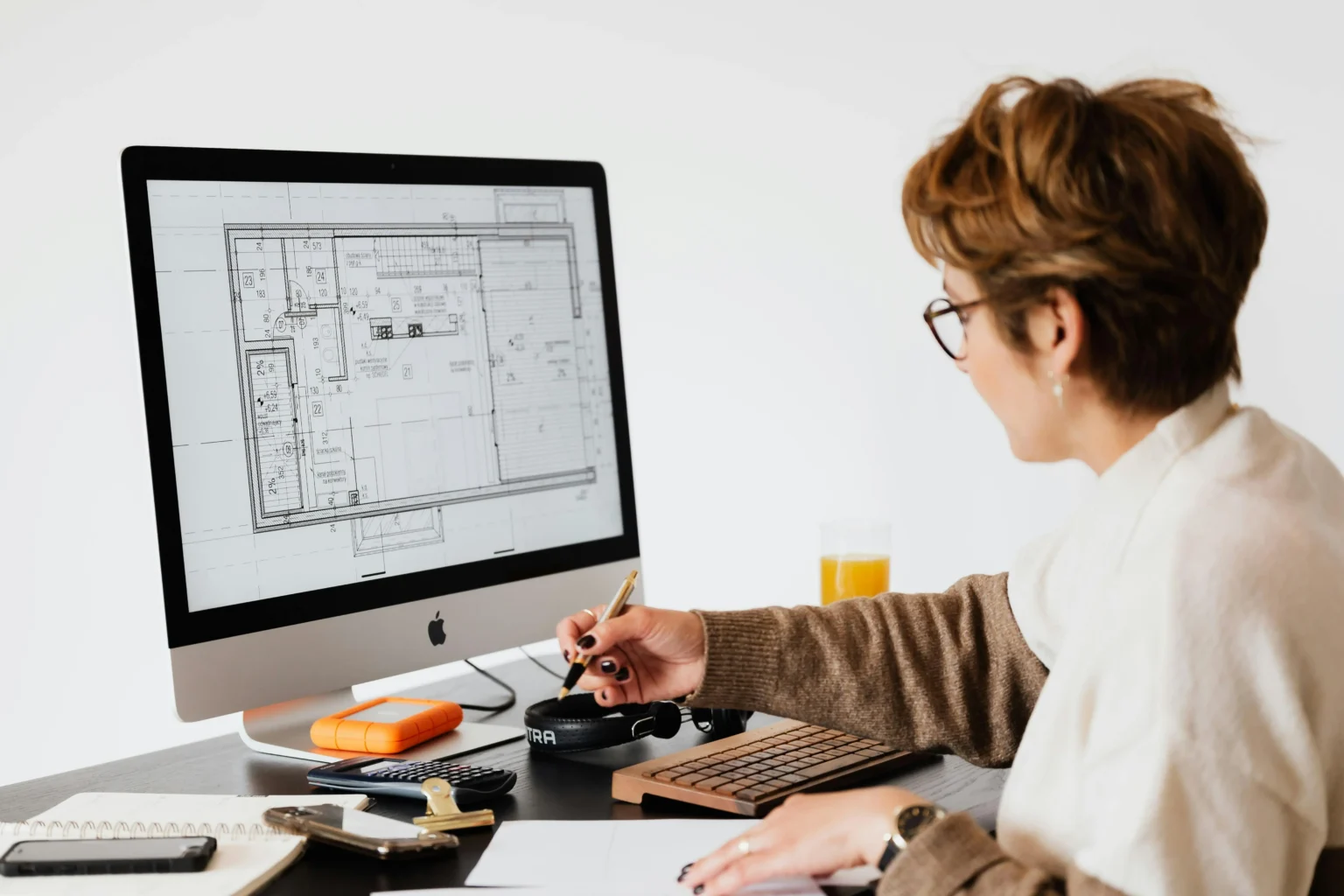 Woman looking at a renovation blueprint on a computer and calculating costs