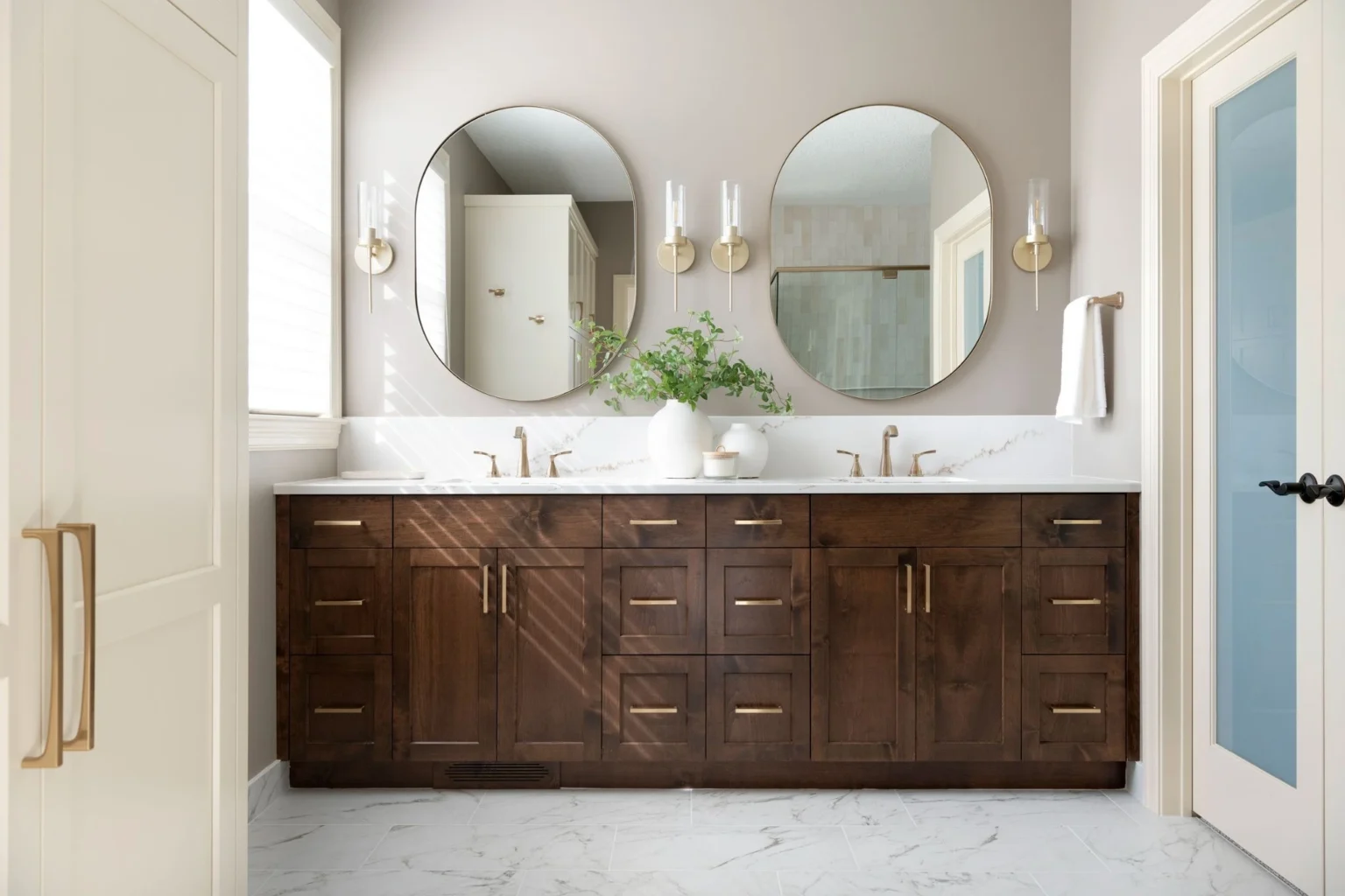 Bathroom with a dark brown wood double vanity and radiant floor heating below white tile